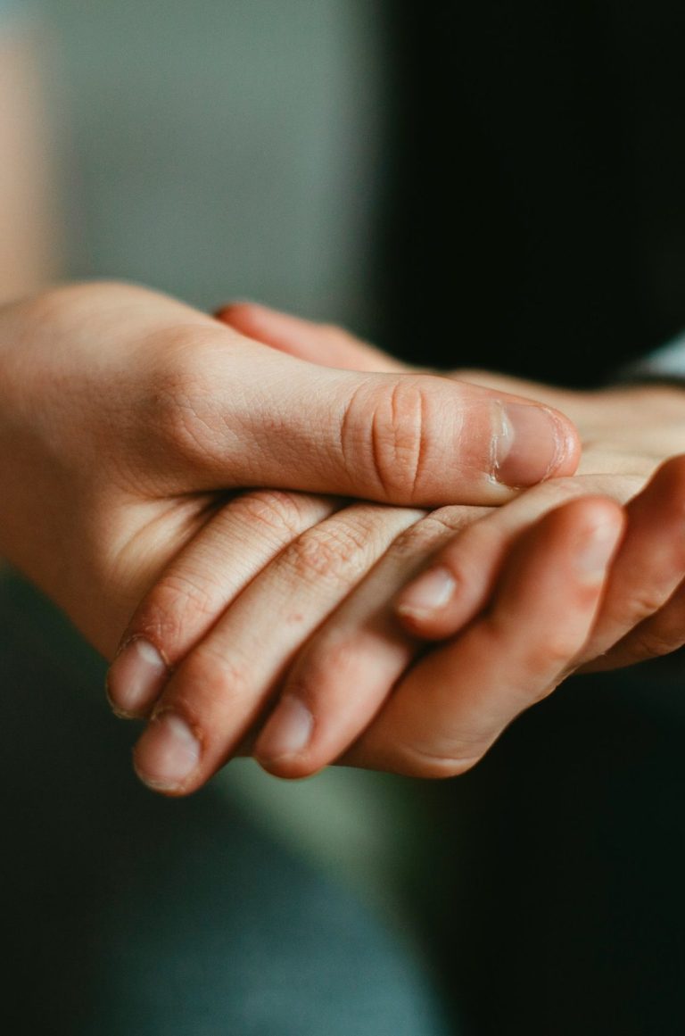 Two people holding hands, offering comfort and support